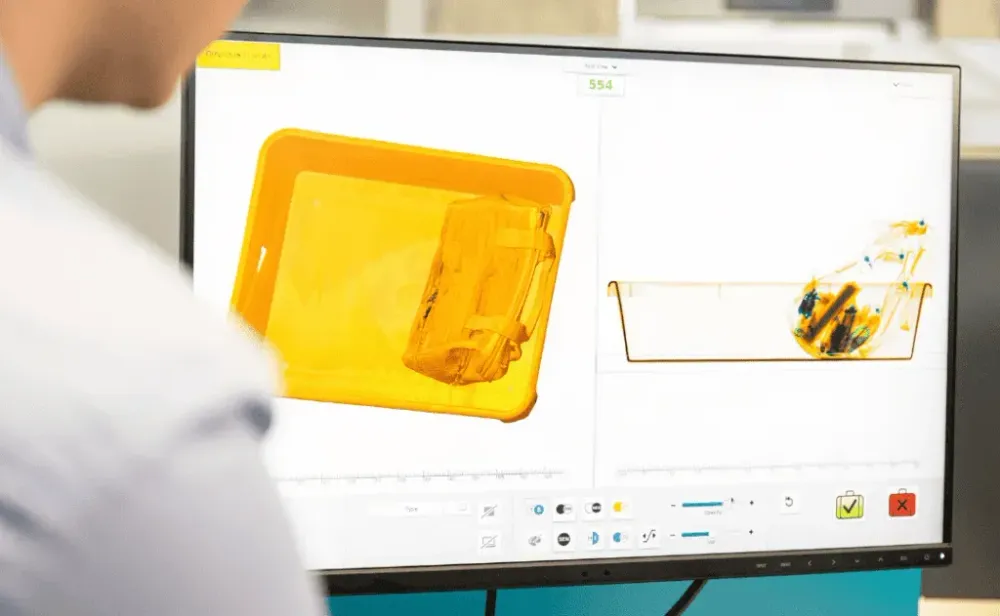 Airport security baggage screening. Security man looking at monitor scanning luggage through x-ray scanner